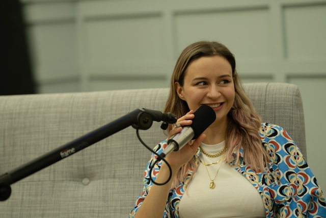 A woman talking to a microphone on a live podcast